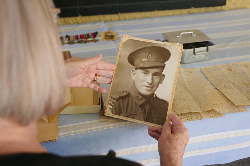 A woman holding an old photo of a man from the war