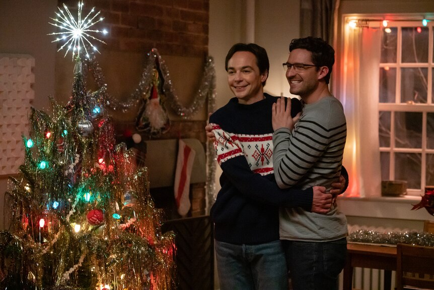 Actors Jim Parsons as Michael Ausiello and Ben Aldridge as Kit Cowan in an embrace next to a Christmas tree