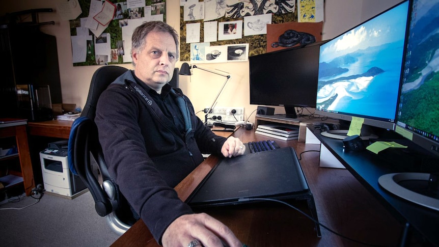 A man sitting at a desk in front of a computer.