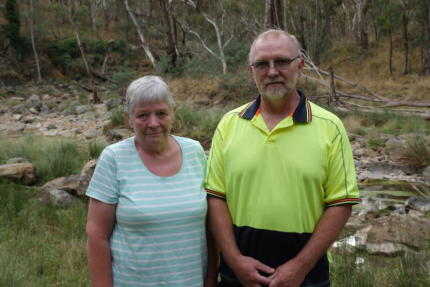 An elderly couple standing in front of a creek 