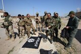 Iraqi soldiers lay an Islamic State flag on the ground.