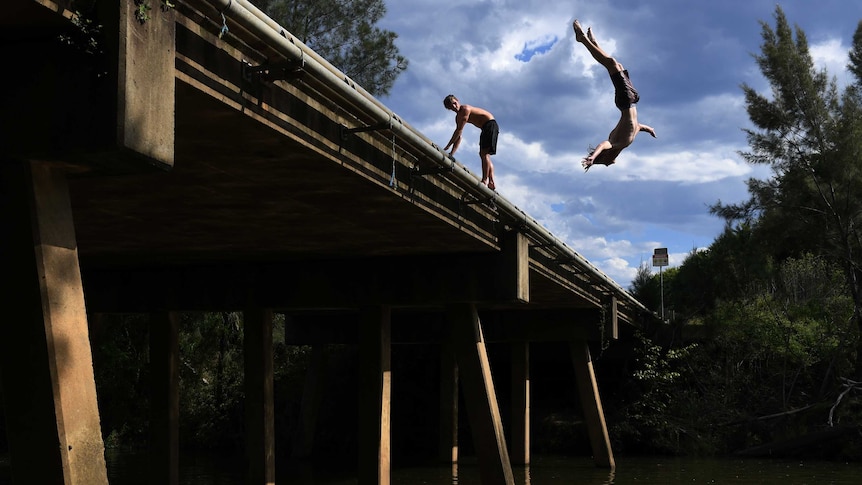 Local boys from Camden jump from the Macquarie Grove Road Bridge into the Nepean River