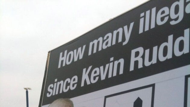 Opposition Leader Tony Abbott changes numbers on a billboard