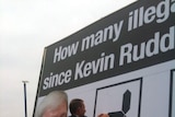 Opposition Leader Tony Abbott changes numbers on a billboard