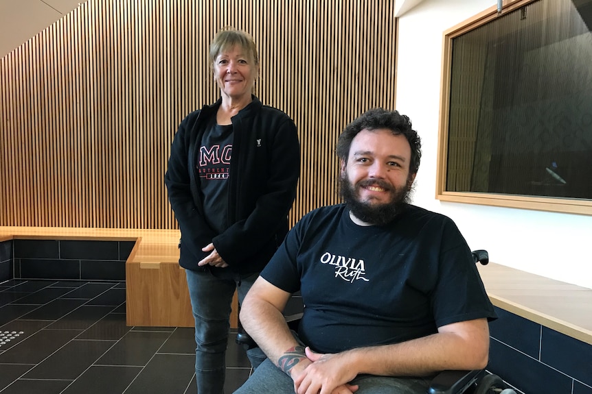 A man in a wheelchair and a woman standing close up him.