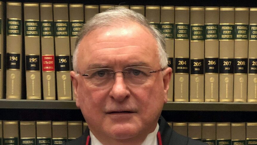 Justice Kevin Bell standing in front of a bookcase.