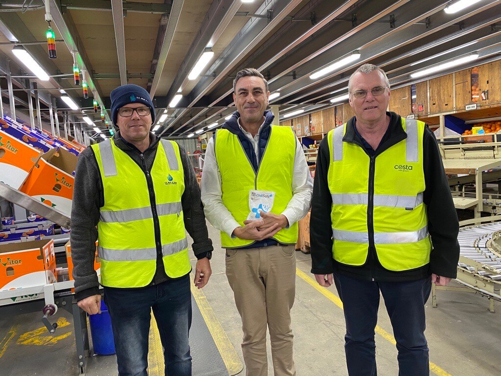 Three men in high vis smiling inside a warehouse
