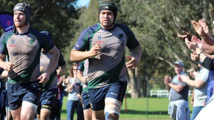 Two men running onto a rugby field.