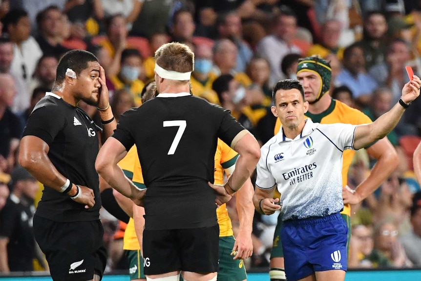 A referee holds up a red card as he sends off a New Zealand All Blacks player against Australia in Brisbane.