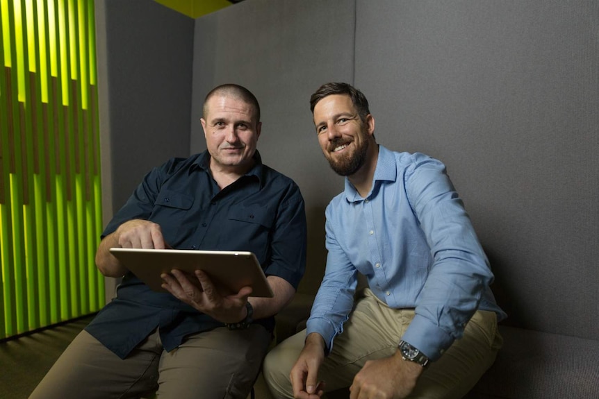 Two men smile at the camera.