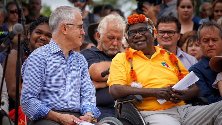 Malcolm Turnbull and Galarrwuy Yunupingu sitting next to each other and smiling at each other.