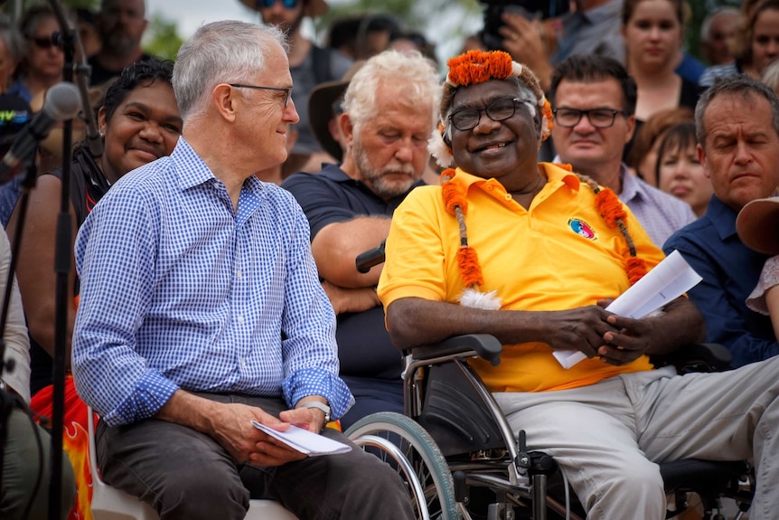 Malcolm Turnbull and Galarrwuy Yunupingu sitting next to each other and smiling at each other.