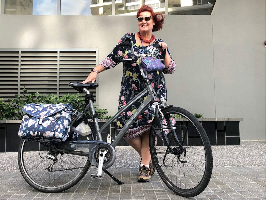 Tae Baker standing by her bike in a dress and sneakers