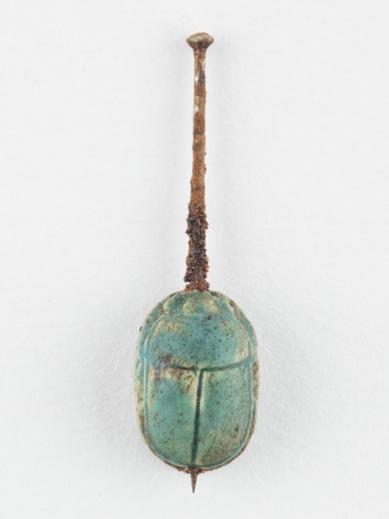 A glazed scarab with a nail through its centre.