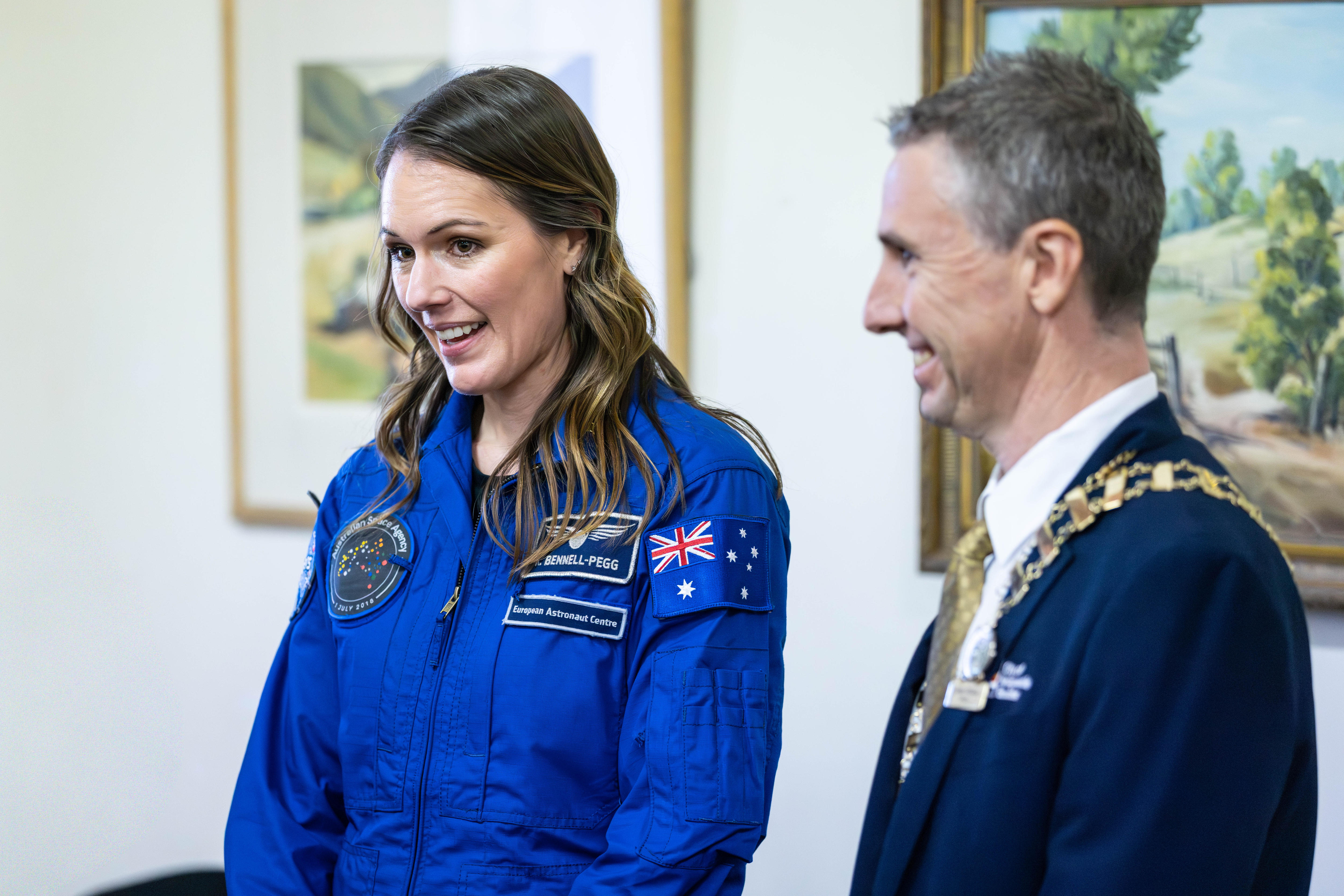 Un astronauta con traje de vuelo junto a un alcalde.  