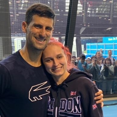 Novak Djokovic stands on court next to a tennis fan at Melbourne Park.