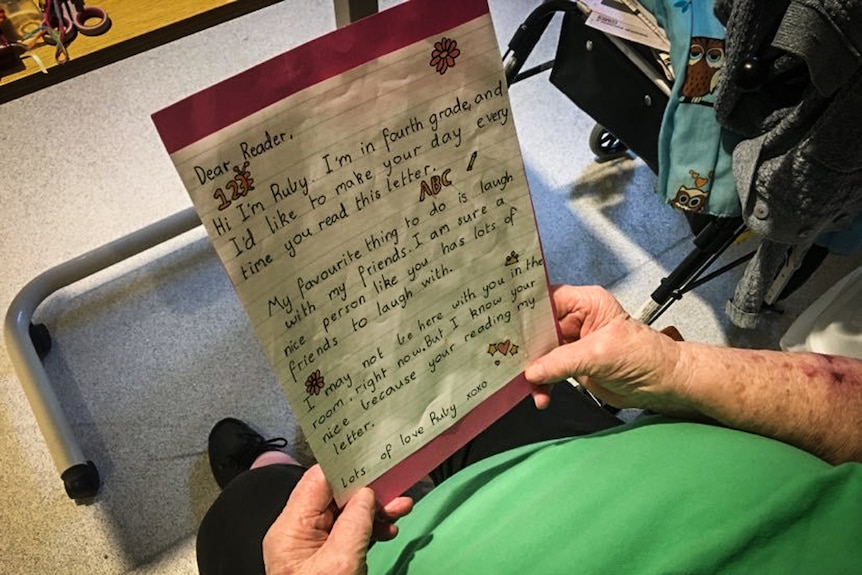 An elderly resident holding a letter from Grade 4 student Ruby.