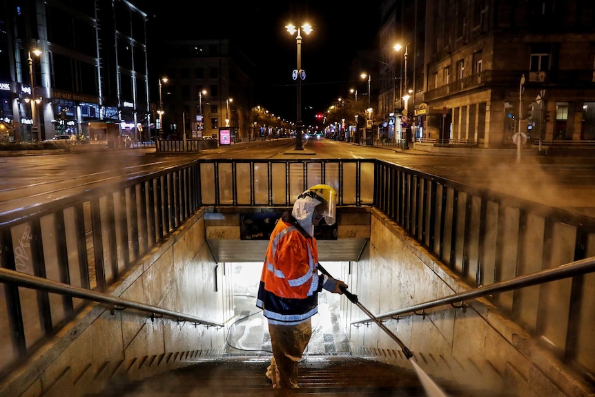 A man in high vis gear spraying disinfectant on steps in Budapest