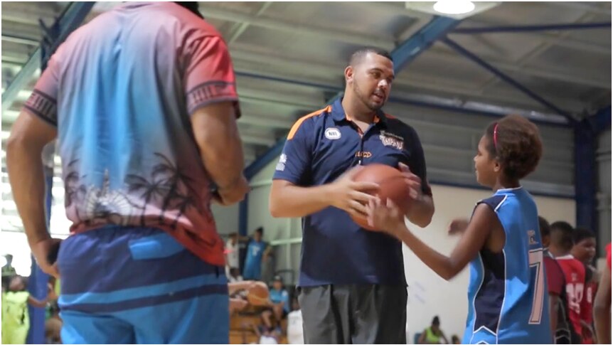 Kerry Williams teaching young children how to play basketball