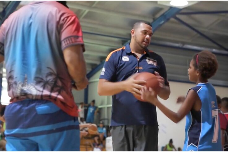 Kerry Williams teaching young children how to play basketball