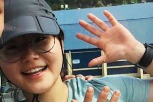 Joohee Han smiles and waves in a selfie, wearing a cap and glasses, date unknown.