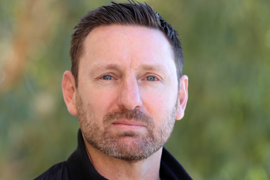 Mr Callaghan looks at the camera, wearing a blue shirt. Background is blurred.