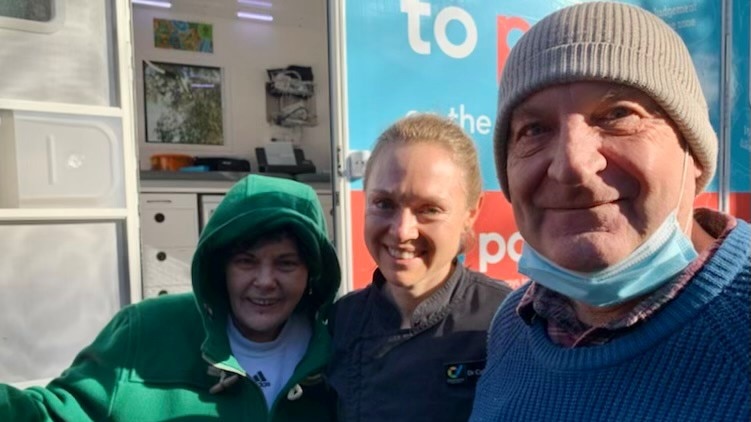 Three people standing in from of PAT mobile health van.