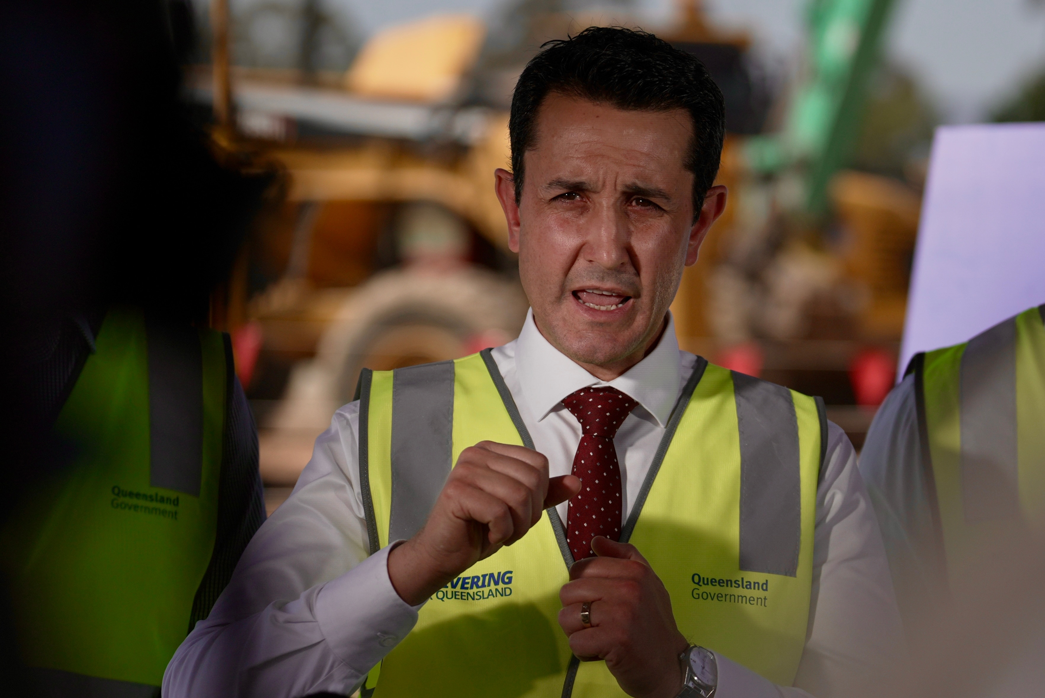 David Crisafulli uses hand gestures while speaking during a press conference at a building site.