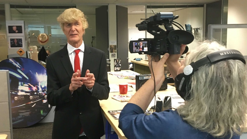 Paul Barry wearing a Donald Trump while being filmed for a Media Bites episode.
