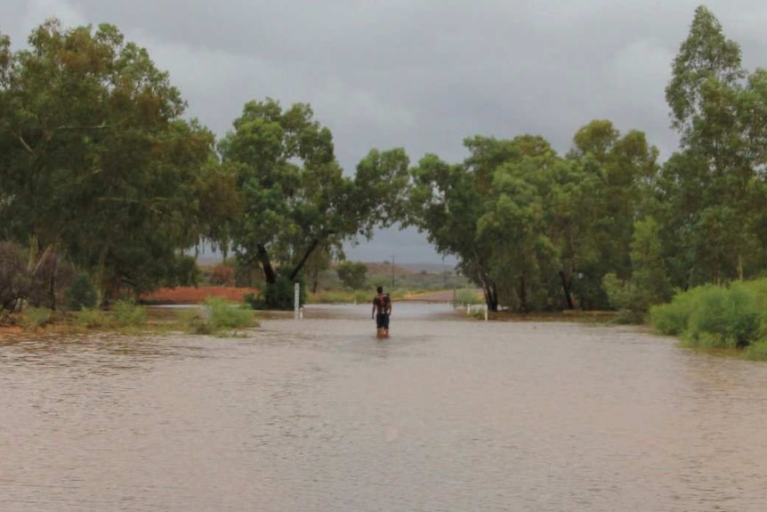 Flooded road with man standing in the middle.