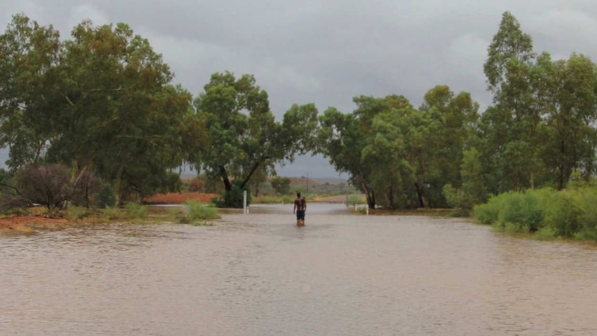 Flooded road with man standing in the middle.