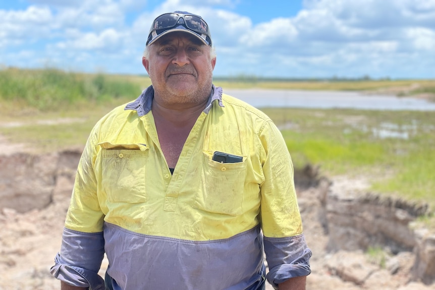 Man in high visibility shirt stands in front of dam 