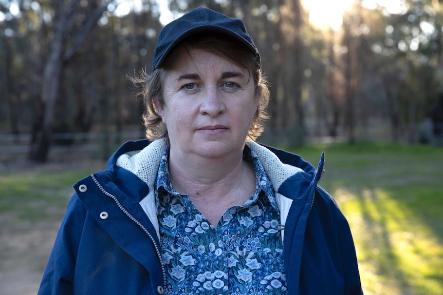 Maryanne Slattery wears a blue floral shirt under a dark blue jacket. She has a neutral facial expression