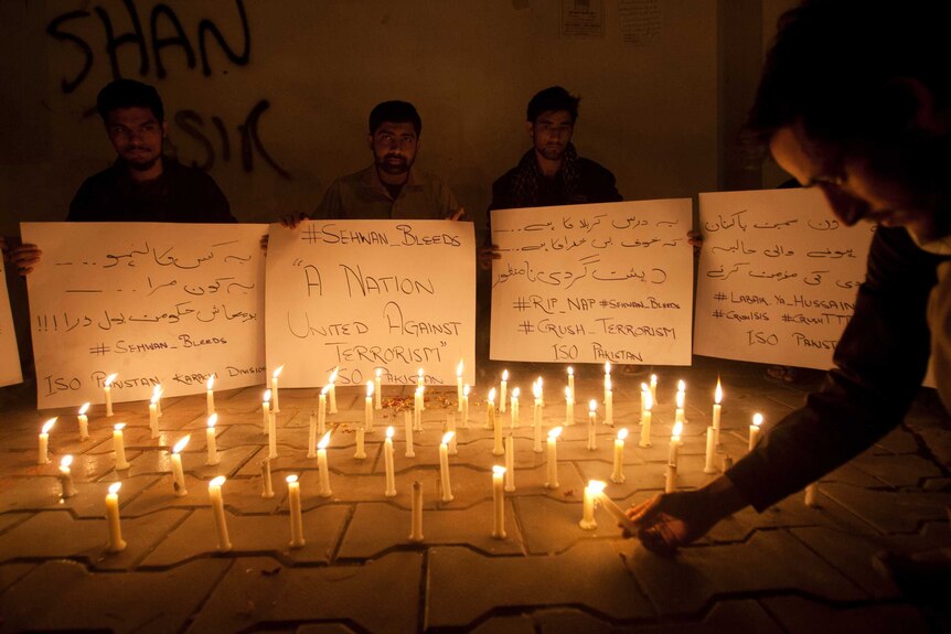 Pakistani students light candles to condemn the recent attack on a shrine.