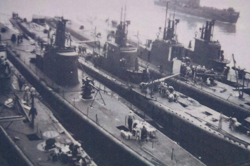 A black and white photo of five American submarines, rafted alongside each other at New Farm Wharf