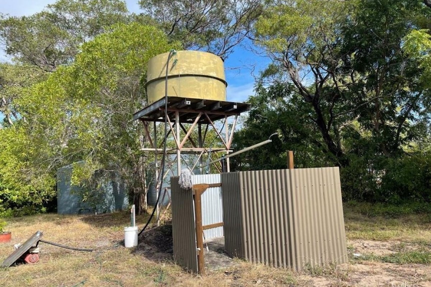 A watertank with an outdoor shower below it. 