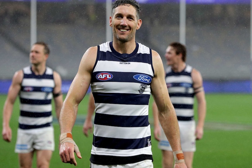 Harry Taylor smiles while walking off the field. Some teammates follow him off