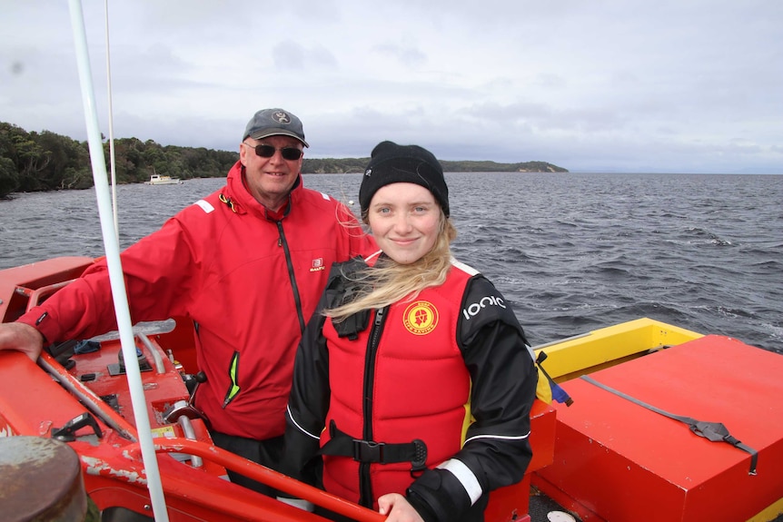 An older man and a young woman in a Surf Life Saving boat.