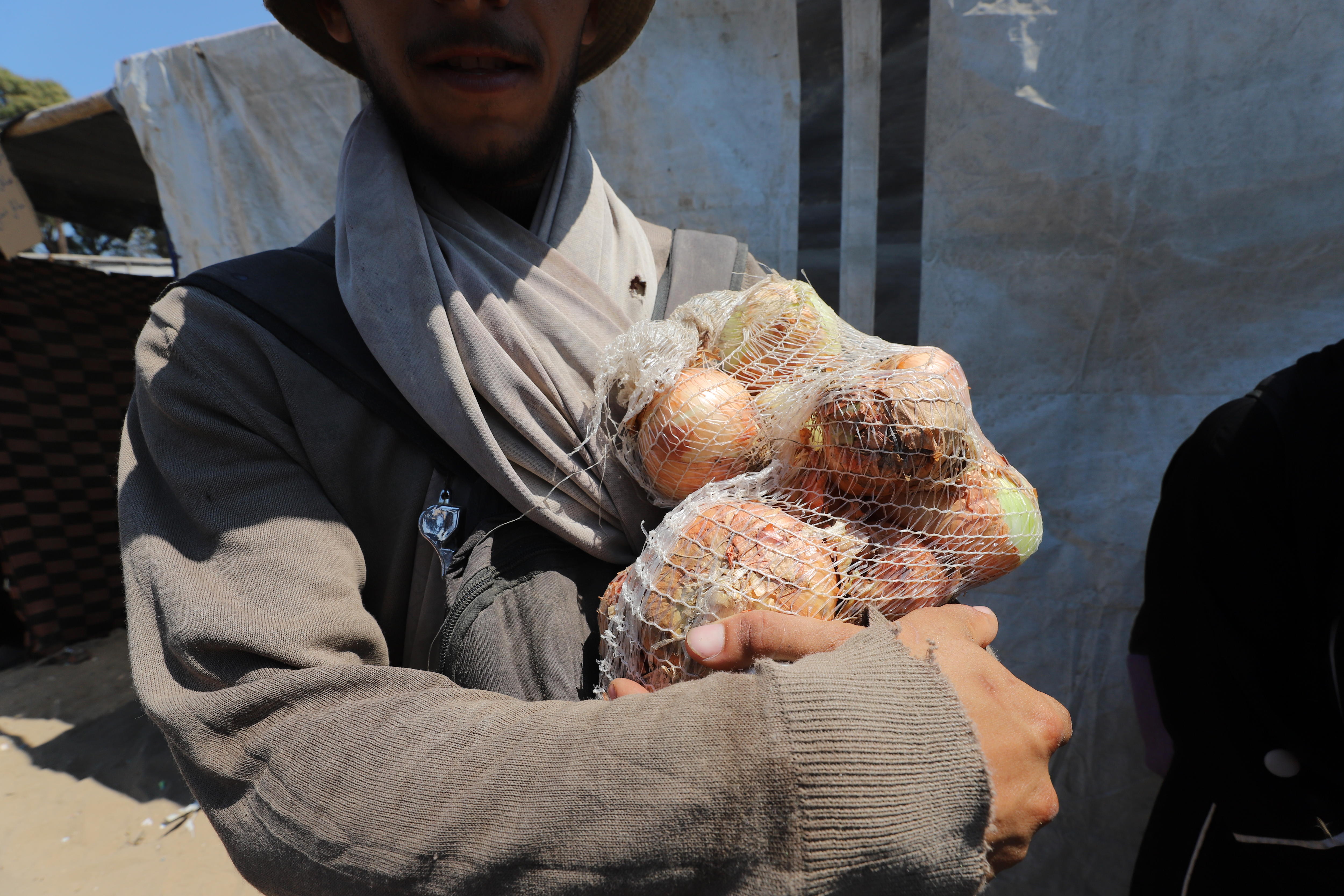 Abu el Majed holds a bag of onions collected from an aid site in Gaza.