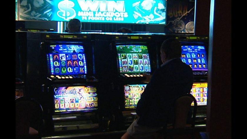 Generic TV still of anonymous silhouetted gambler playing pokies in Queensland.