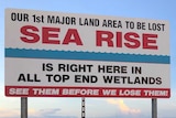 A sign says: Our 1st major land area to be lost to sea rise is right here in all Top End wetlands. See them before we lose them!