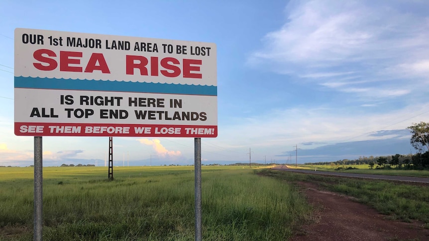 A sign says: Our 1st major land area to be lost to sea rise is right here in all Top End wetlands. See them before we lose them!