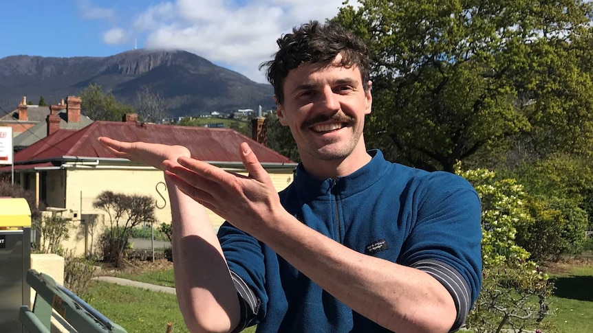 Geologist and artist Till Gallagher holding his hands in front of Mount Wellington