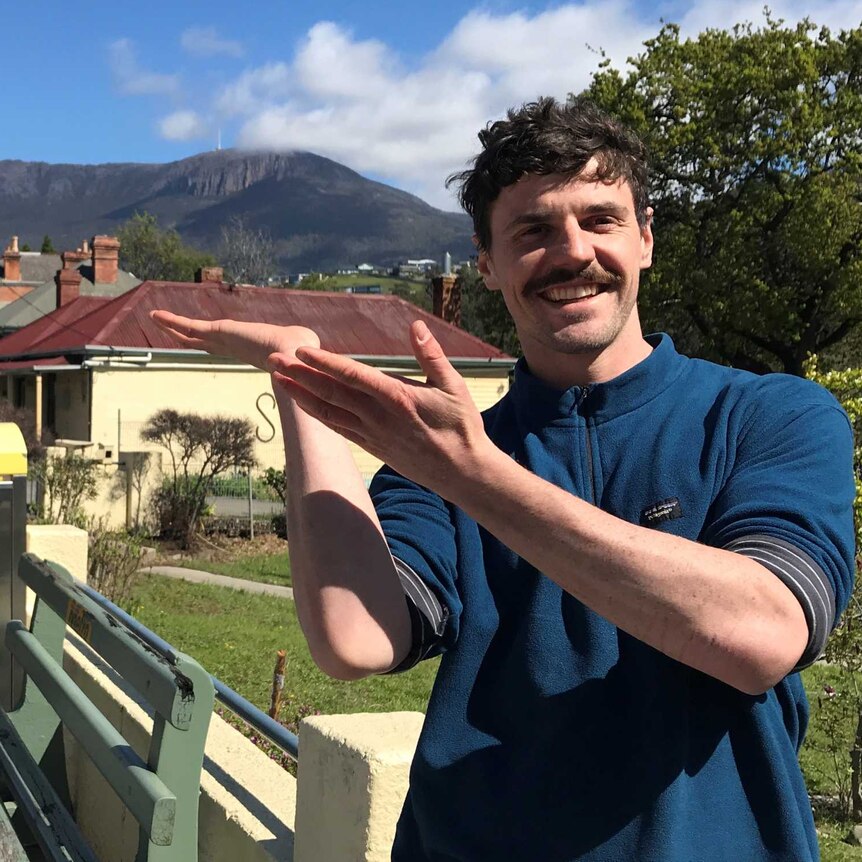 Geologist and artist Till Gallagher holding his hands in front of Mount Wellington