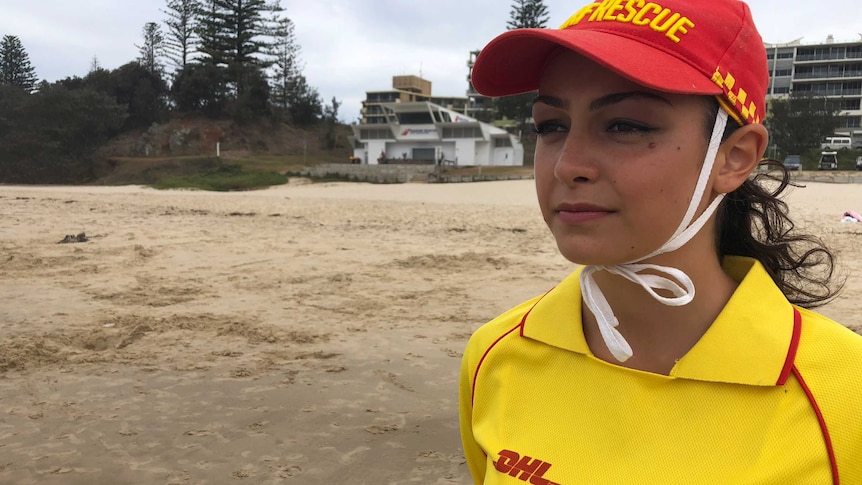 A young woman wearing a surf lifesaving uniform at the beach