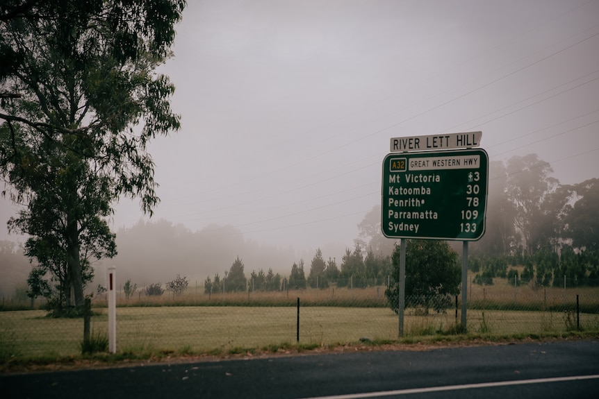Great Western Highway sign at River Lett Hill, overcast sky, green tree.