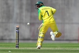 A batsman wearing a helmet grimaces and flinches after a ball hits him.