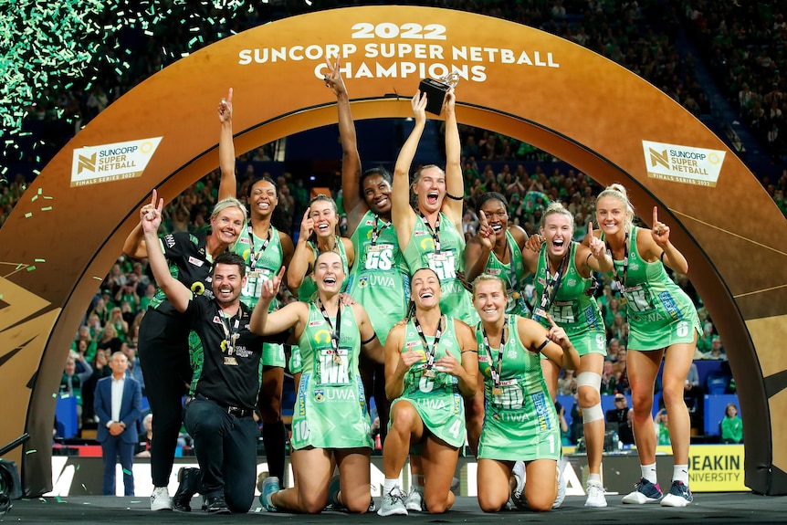 Team shot of netballers underneath a golden 2022 Suncorp Super Netball Champions arch.