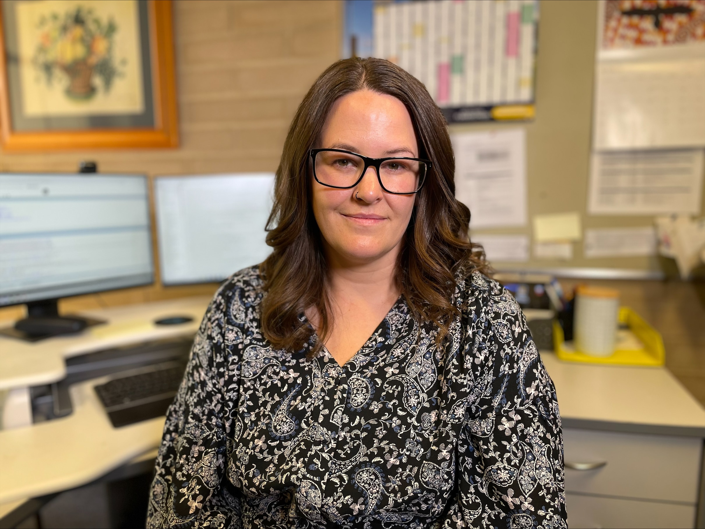 A brunette woman sitting in front of an office desk