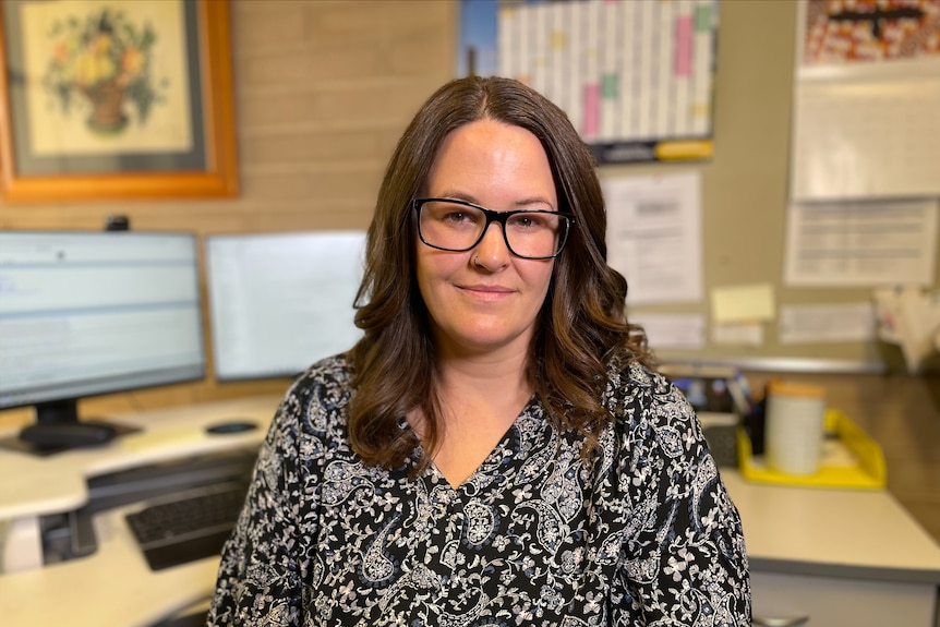 A brunette woman sitting in front of an office desk